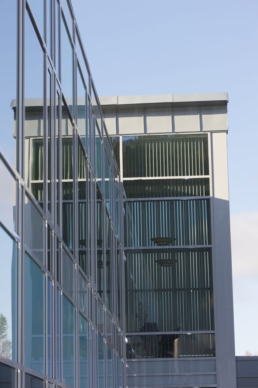 Moderne glassbygning med reflekterende vinduer mot en klar blå himmel. Foto: Nathan Lediard, Lediard Foto AS.