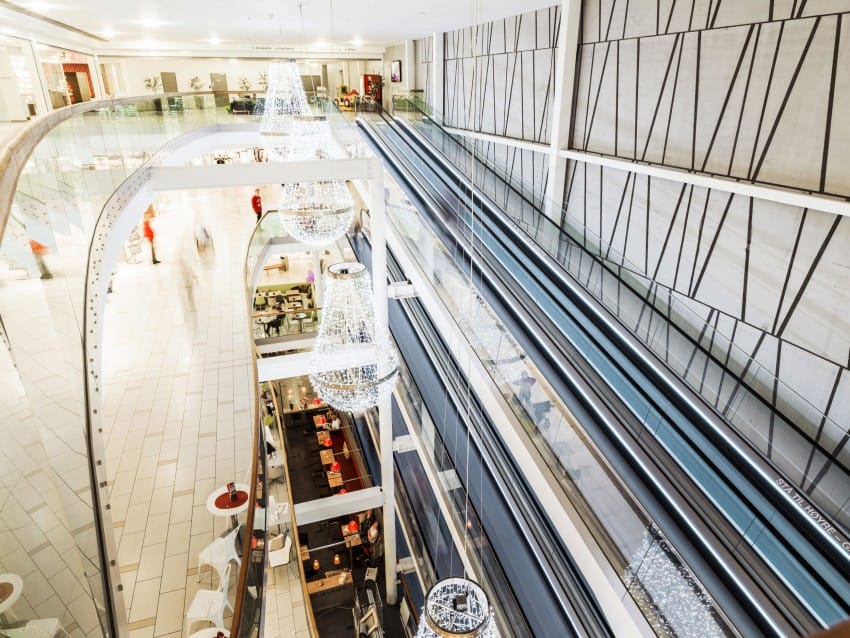 Moderne kjøpesenterinteriør med store rulletrapper, geometriske veggmønstre og dekorative lysekroner. Foto: Nathan Lediard, Lediard Foto AS.