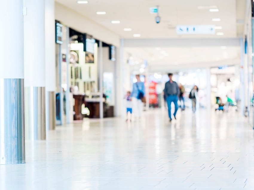 Uskarp utsikt over et romslig, godt opplyst kjøpesenter med folk som går og butikker på hver side. Foto: Nathan Lediard, Lediard Foto AS.