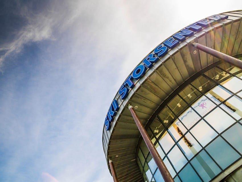 Buet bygning med "Ski Storsenter"-skilting mot en blå himmel med strie skyer. Foto: Nathan Lediard, Lediard Foto AS.