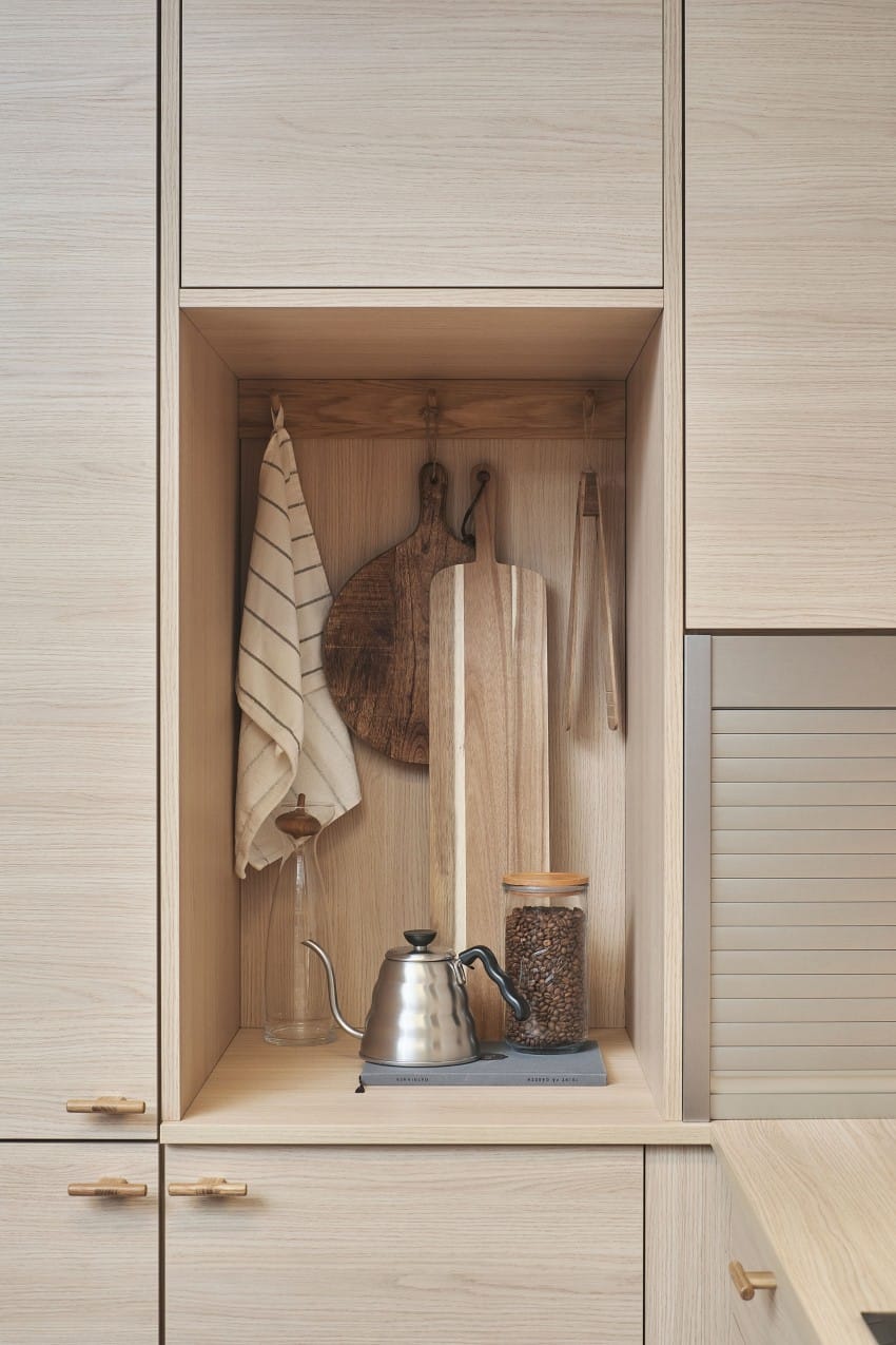 Minimalistisk kjøkkenkrok med treplater, et stripete håndkle, en vannkoker og en krukke med kaffebønner på en hylle i lyst tre. Foto: Nathan Lediard, Lediard Foto AS.