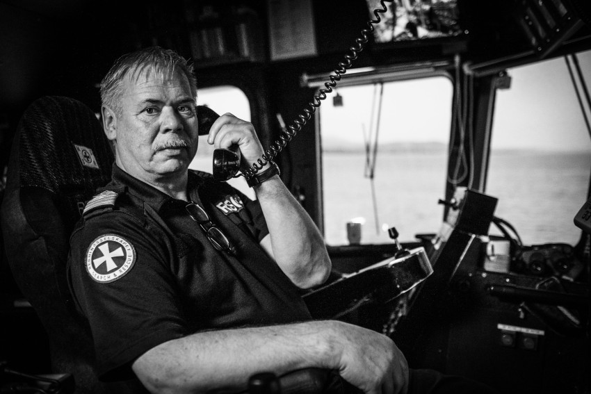 Mann i marineuniform snakker i telefon i et skips kontrollrom, med vinduer som viser havet i bakgrunnen. Foto: Nathan Lediard, Lediard Foto AS.