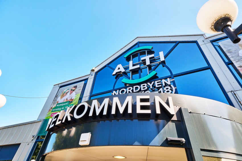 Moderne bygg med store vinduer, med skilt "ALTI NORDBYEN" og "VELKOMMEN" over inngangspartiet. Foto: Nathan Lediard, Lediard Foto AS.