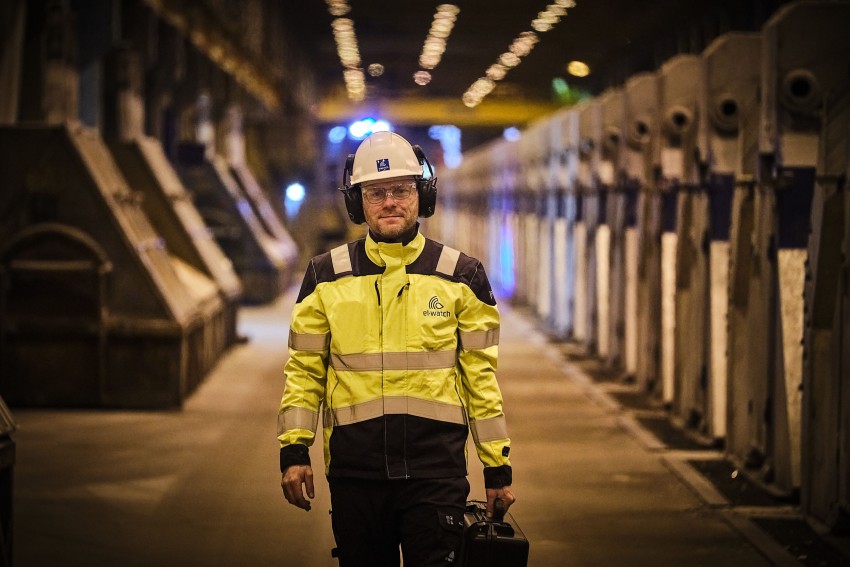 Arbeider i verneutstyr går gjennom et industrianlegg med maskiner på begge sider. Foto: Nathan Lediard, Lediard Foto AS.