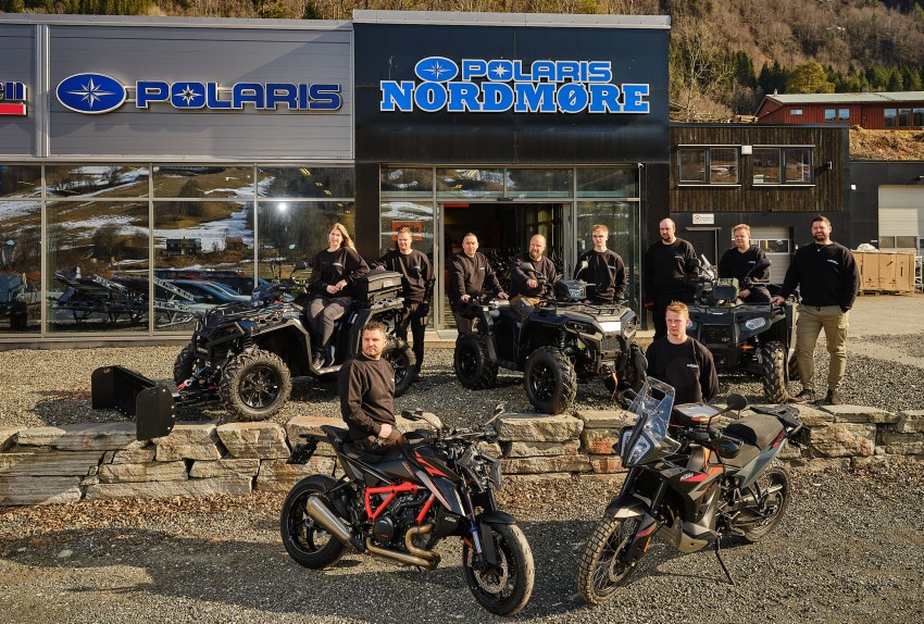 En gruppe mennesker poserer med ATV-er og motorsykler foran en Polaris Nordmore-forhandler. Foto: Nathan Lediard, Lediard Foto AS.