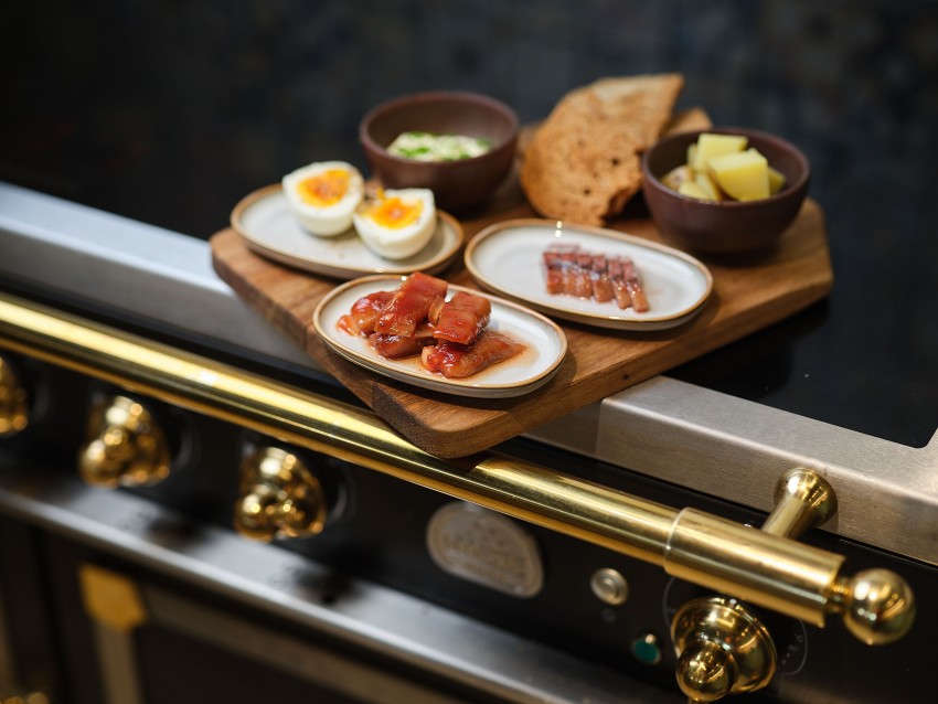 En treplate på en komfyr med egg, kjeks, ost, ansjos og oppskåret kjøtt på små tallerkener. Foto: Nathan Lediard, Lediard Foto AS.