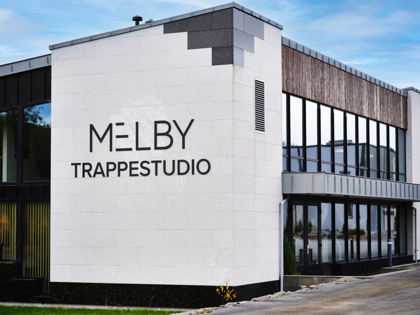Moderne bygg med store vinduer og "MELBY TRAPPESTUDIO" skilt på fasaden. Foto: Nathan Lediard, Lediard Foto AS.