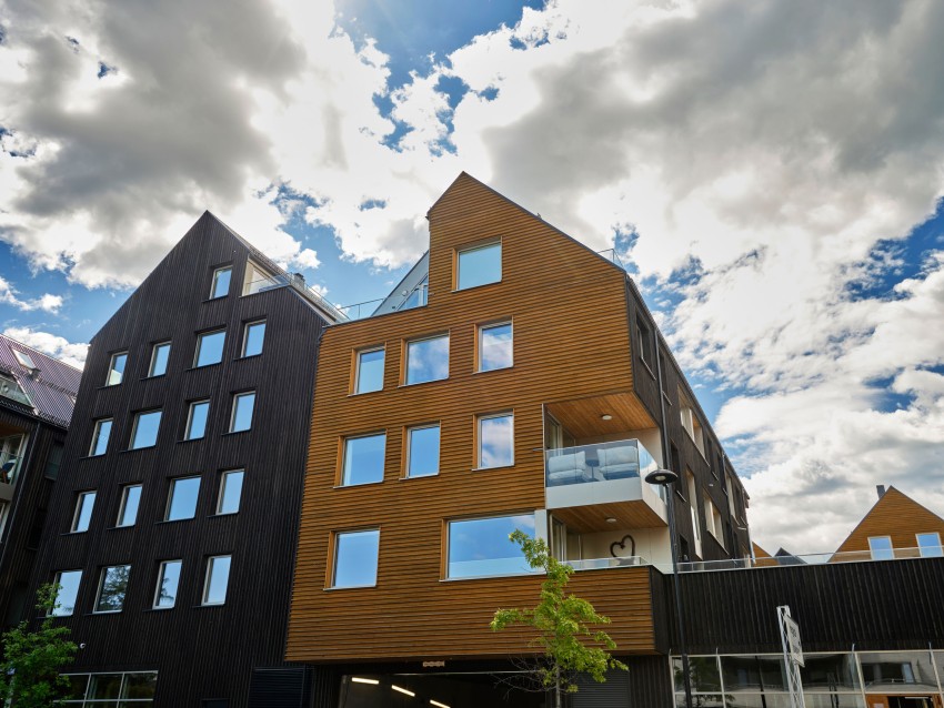 Moderne trebygninger med store vinduer under en delvis overskyet himmel. Foto: Nathan Lediard, Lediard Foto AS.