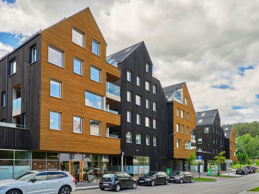 Moderne bolighus i tre med biler parkert foran, under overskyet himmel. Foto: Nathan Lediard, Lediard Foto AS.