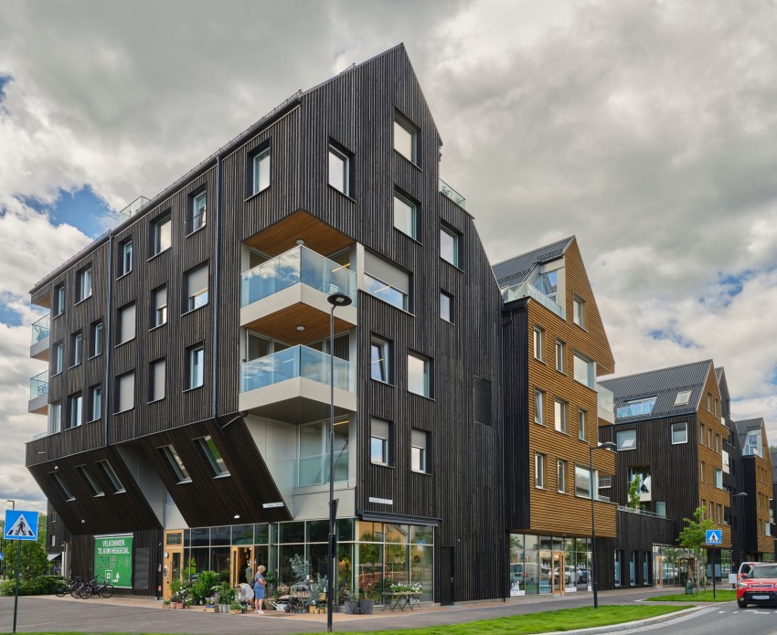 Moderne fleretasjes bygning med mørk trefasade og glassbalkonger under overskyet himmel. Foto: Nathan Lediard, Lediard Foto AS.