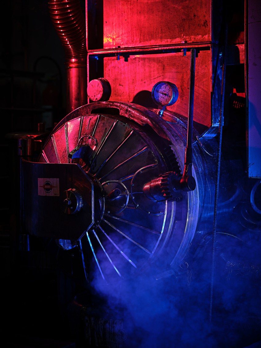 En industrimaskin med fargerik rød og blå belysning, omgitt av tåke eller røyk. Foto: Nathan Lediard, Lediard Foto AS.