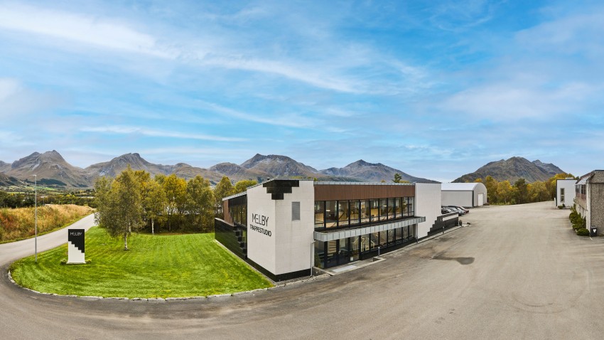Moderne bygg med skilt "Kjeldby" mot et bakteppe av fjell og klarblå himmel. Foto: Nathan Lediard, Lediard Foto AS.