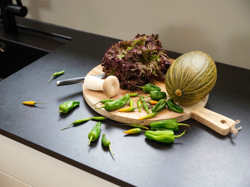 Et skjærebrett med salat, en melon, grønn paprika, en kniv og en morter på en svart benkeplate. Foto: Nathan Lediard, Lediard Foto AS.