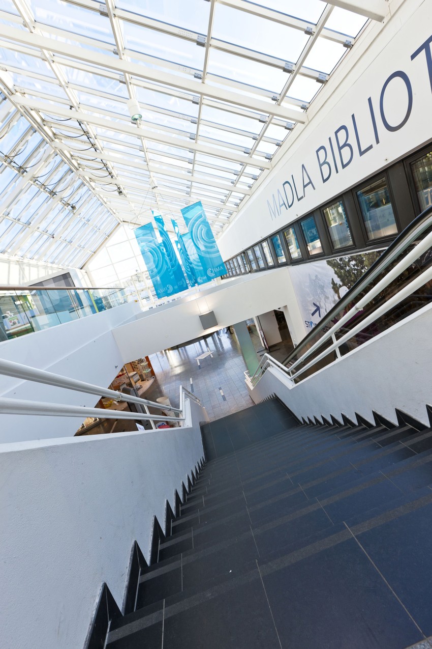 Trapp i moderne bygning med glasstak og skilt med "Madla Bibliotek". Foto: Nathan Lediard, Lediard Foto AS.